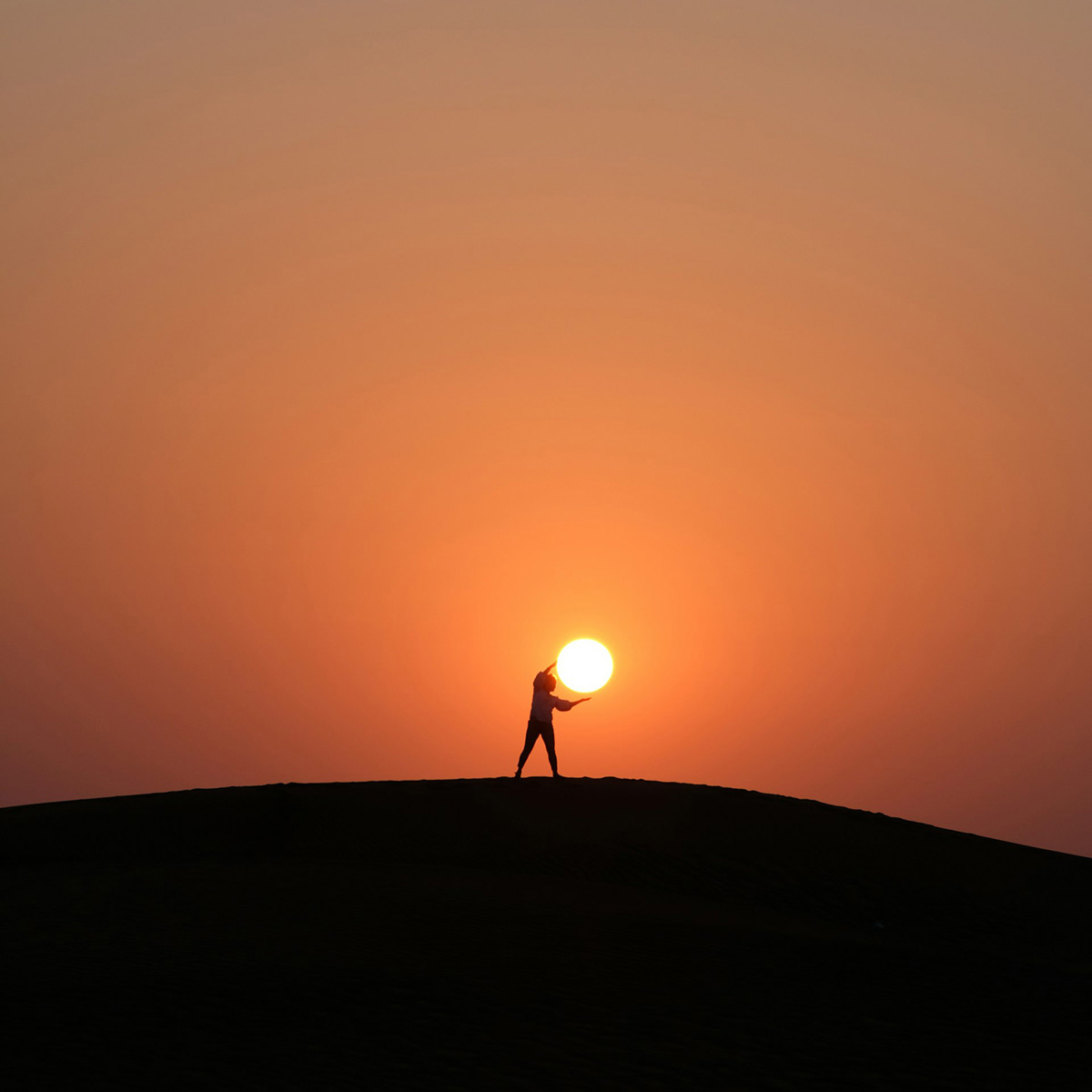 A silhouette of person standing on a hill duringsunset